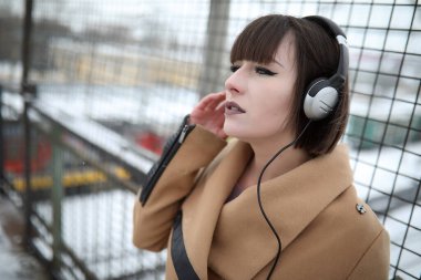 Kulaklık takıp açık havada müzik dinleyen tatlı bir kız.