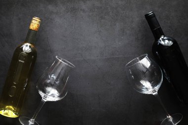 Masada bir bardak kırmızı şarap. Siyah şişe ve bir bardak şarap..