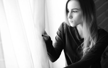 Genç bir kız büyük bir dairede dinleniyor.