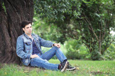 Genç bir adam öğle yemeği zamanında parkta yürür. Bir adam şehirde gezintiye çıktı. Park eden bir öğrenci.