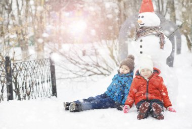 Kışın parktaki çocuklar. Çocuklar parkta karla oynarlar. Kardan adam heykeli yapıp tepelerden aşağı kayıyorlar..