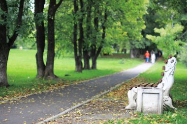 Gözlüklü genç bir adam yağmur sırasında elinde şemsiyeyle parkta yürür..