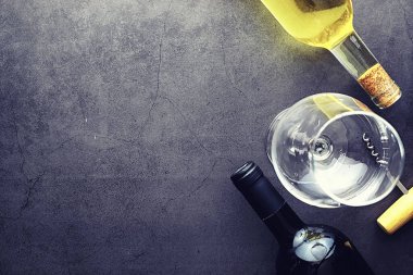 Masada bir bardak kırmızı şarap. Siyah şişe ve bir bardak şarap..