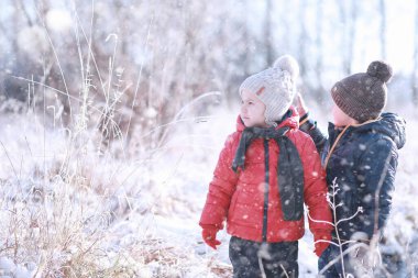 Çocuklar parkta ilk karla yürür.