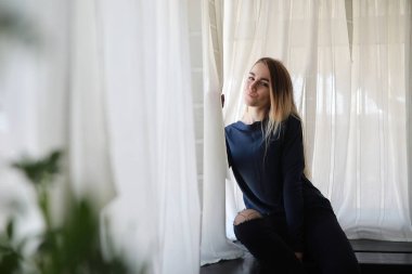 Genç bir kız büyük bir dairede dinleniyor.