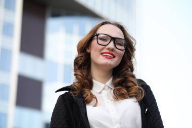 Binanın arka planında katı giysiler içindeki iş kadını.