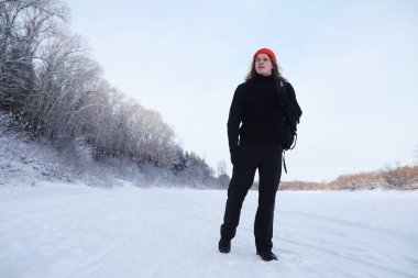 Bir adam sırt çantasıyla seyahat eder. Ormanda kış yürüyüşü. Kışın parkta yürüyüş yapan bir turist..