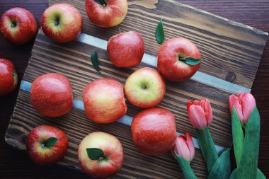 Tahtadaki taze elmalar. Kırmızı elma hasadı. Masada meyve ve tarçın var..