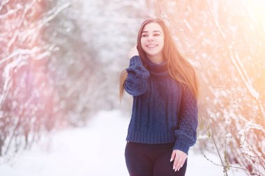 Kış parkında yürüyüş yapan genç bir kız. Kış ormanlarında Noel tatili. Kız parkta kışın tadını çıkarıyor.