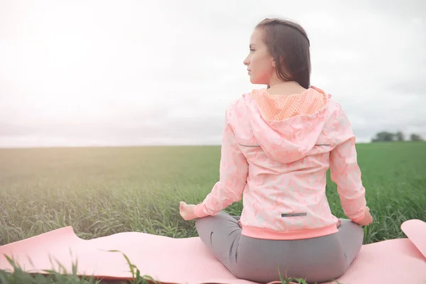 The girl in yoga on the outdoor in a field