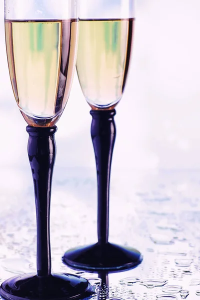 Background with tall glasses for sparkling wines. Champagne spray in glass glasses. Celebratory drink with reflection.