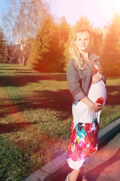 Pregnant girl on a walk in the park. Girl with a belly in the city park. Future mom is walking in the park