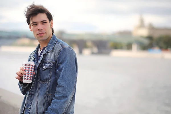 A young man walks in the park at lunch time. A man is on a walk in the city. A student in park