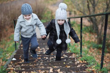 Çocuklar sonbahar parkında sonbaharda yürürler