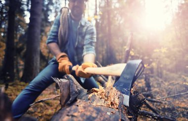 Ormanda ağaç kesen baltalı bir erkek işçi..