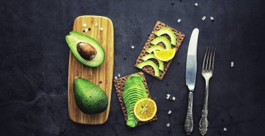 Avokado yemek tarifleri. Tahta kesme tahtasında servis edilen olgun yeşil avokado..