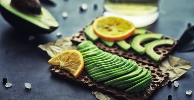 Avokado yemek tarifleri. Tahta kesme tahtasında servis edilen olgun yeşil avokado..