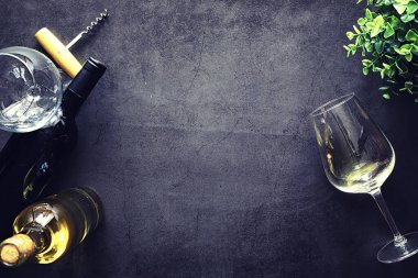 Masada bir bardak kırmızı şarap. Siyah şişe ve bir bardak şarap..