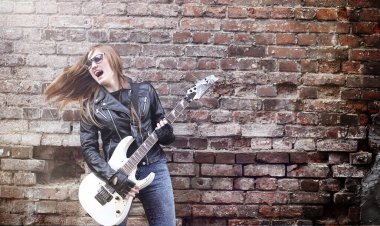 Güzel genç kız rocker elektro gitar ile. Bir gitar ile deri ceketli bir rock müzisyen kız şarkı söylüyor. Rock band solist gitar çalıyor ve mikrofona bağırır.