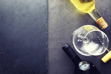 Masada bir bardak kırmızı şarap. Siyah şişe ve bir bardak şarap..