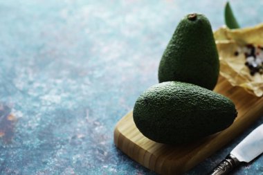 Avokado yemek tarifleri. Tahta kesme tahtasında servis edilen olgun yeşil avokado..