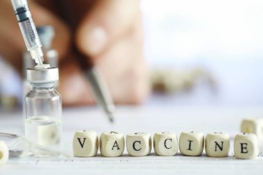 Bir adam tıbbi belge imzalıyor. Tıbbi ekipmanlar masada. Stetoskop ve şırıngalı ampuller. Ofiste notlar alıyor. Tıp Merkezi.