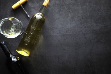 Masada bir bardak kırmızı şarap. Siyah şişe ve bir bardak şarap..