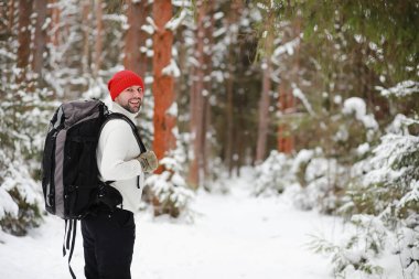 Bir adam sırt çantasıyla seyahat eder. Ormanda kış yürüyüşü. Kışın parkta yürüyüş yapan bir turist..
