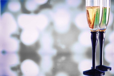 Köpüklü şaraplar için uzun bardaklı bir arka plan. Cam bardaklarda şampanya spreyi. Yansımalı kutlama içkisi.