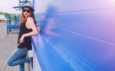 Güneş gözlüklü ve şapkalı genç kız. Duvardaki hippi kız. Sokakta şapkalı ve gözlüklü bir genç