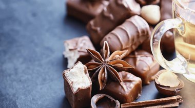 Arkaplanda siyah arka planda çikolatalar. Doldurulmuş çikolata. Atıştırmalık tatlı ve çay.