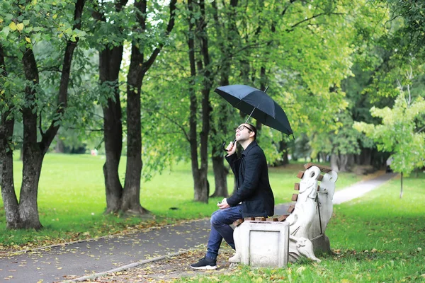 Gözlüklü Genç Bir Adam Yağmur Sırasında Elinde Şemsiyeyle Parkta Yürür — Stok fotoğraf