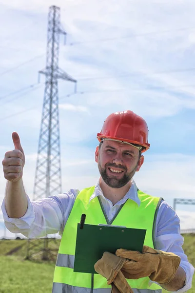 Electrician working in a helmet wearing gloves stand in a field