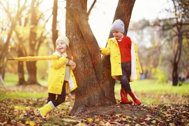 Çocuklar sonbahar parkında sonbaharda yürürler