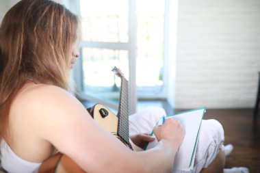 Akustik gitarlı, uzun saçlı genç bir adam.