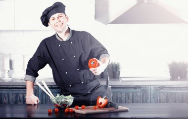 Adam mutfak masasında sebze pişiriyor.