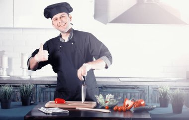 Adam mutfak masasında sebze pişiriyor.