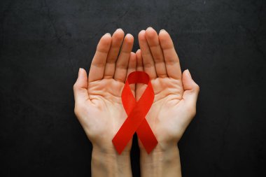 İnsan bağışıklık yetmezliği virüsü hastalığının sembolü. Kırmızı kurdele. Yardım eli ve destek. Arkaplan.