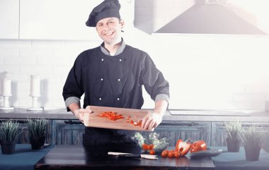 Adam mutfak masasında sebze pişiriyor.