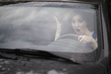 Araba süren bir kız. Yüzünde kötü duygular.