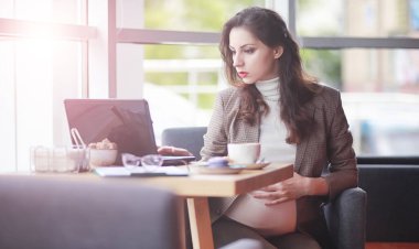 Yemekte kafede bilgisayar başında çalışan hamile bir kadın.