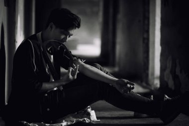 Genç bir adam terk edilmiş bir evde uyuşturucu kullanıyor.