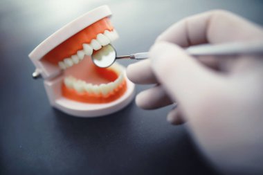 Dişçinin ofisi. Dişçi ağız boşluğu tedavisini inceliyor. Doktor bir tedavi yöntemi gösteriyor. Tedavi görüyor. Kaplamaların yerleştirilmesi ve yerleştirilmesi.