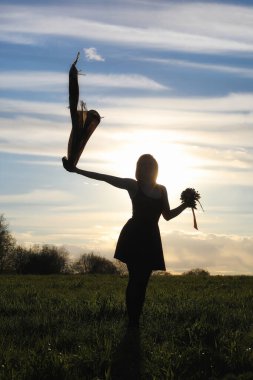 Parkta yürüyüş yapan şapkalı bir kız. Baharda elinde sepet olan bir kız yürür. Kız gün batımında yolda yürüyor.