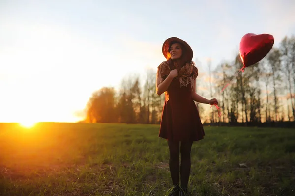 A girl in a hat on a walk in the park. A girl with a basket walks in the spring. Girl is walking along the road at sunset