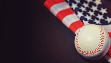 Amerikan geleneksel spor oyunu. Beyzbol mu? Kavram. Amerikan bayrağıyla birlikte beyzbol topu ve sopalar masada..