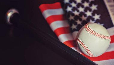 Amerikan geleneksel spor oyunu. Beyzbol mu? Kavram. Amerikan bayrağıyla birlikte beyzbol topu ve sopalar masada..