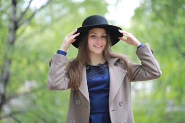 Yağmurda bahar parkında palto giymiş genç bir kız.