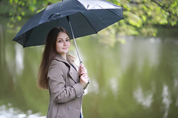 雨の中の春の公園のコートの若い女の子 — ストック写真