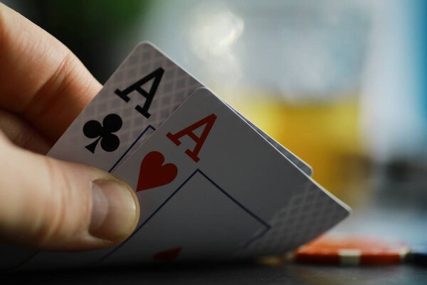 Карточные игры за деньги. Техасский Холдем Покер. Карты в руке, игральные фишки, колода карт с алкоголем в стакане.